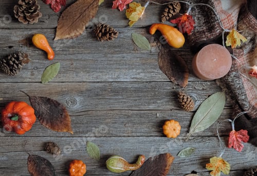 Preview: Autumn frame made of leaves, pine cones, a candle and a scarf on the table.