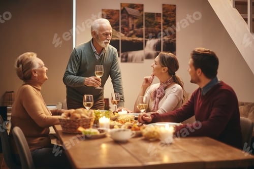 Preview: Happy senior man proposing a toast during family dinner at dining table.