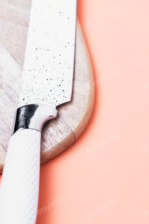 Preview: Cooking concept. Cutting board with a white kitchen knife on a pink background.
