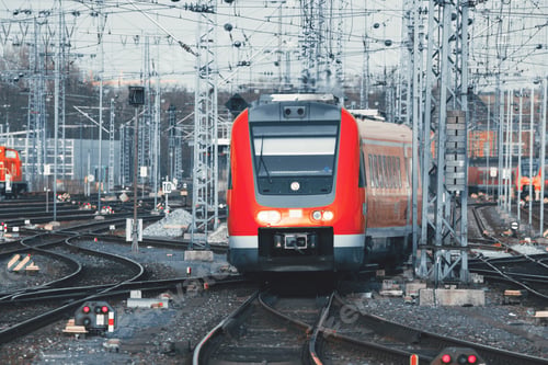 Preview: Railway station with modern red commuter train at sunset
