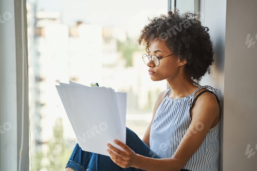 Preview: Young serious beautiful curly-headed female with documents