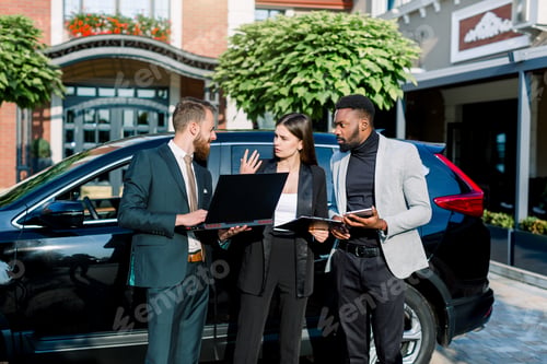 Preview: Multiethnical business group, two men and woman using or looking at tablet and laptop and discuss