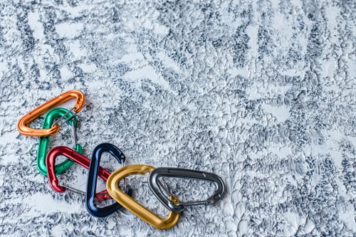 Preview: Isolated photo of climbing equipment. Part of carabiner lying on the white and grey colored surface