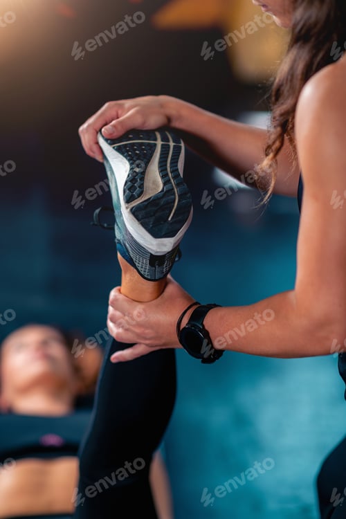Preview: Stretching a mid adult woman in the gym, a personal trainer improves her mobility