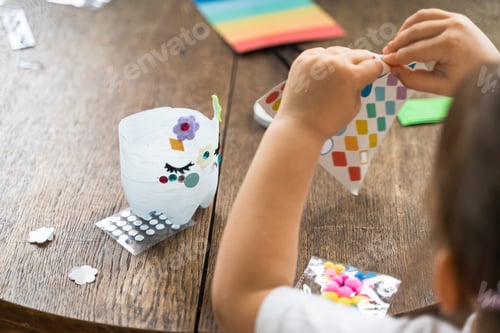 Preview: Caucasian preschool girl doing crafts with plastic bottle and paints. Recycle upcycling waste