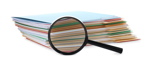 Preview: Stack of colorful folders with documents and magnifying glass isolated on white