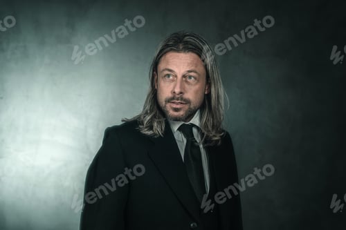 Preview: Retro Victorian Style Man With Blond Long Hair And Beard. Wearing Black Suit And Tie.