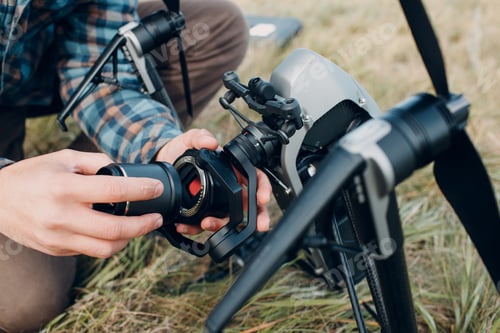 Preview: Man pilot checking quadcopter drone before aerial flight and filming.