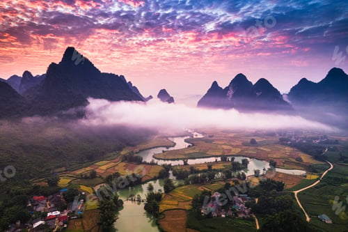 Preview: Sunrise over mountain range with foggy, river and traditional village in Phong Nam Valley