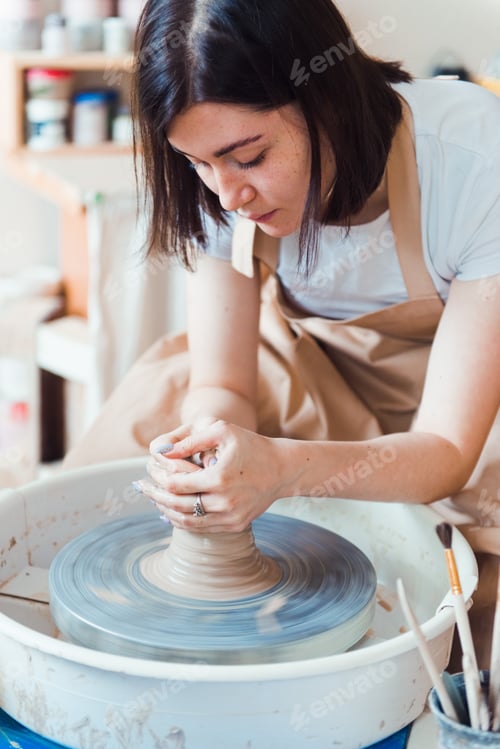 Preview: Woman creating pottery on a spinning wheel indoors
