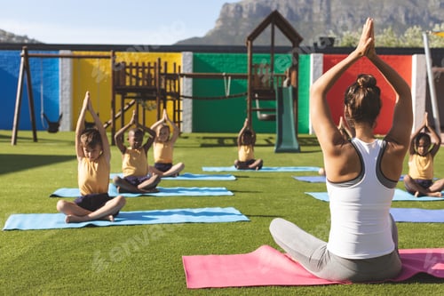Preview: Trainer teaching yoga to students on yoga mat in school playground at schoolyard