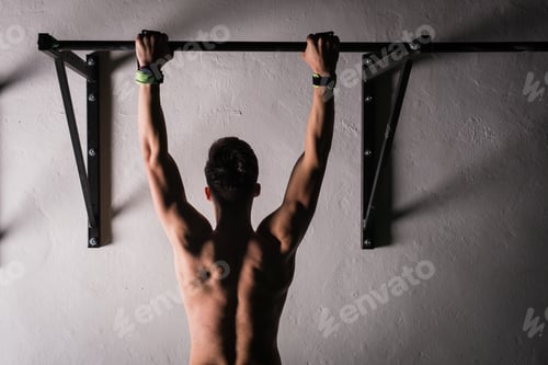 Preview: Man hanging on bar near wall in gym