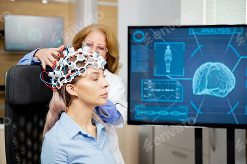 Preview: Doctor arranging scanning device on head of a female patient