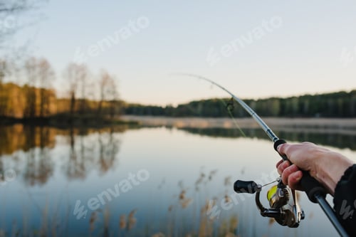 Preview: Fisherman with rod, spinning reel on the river bank. Sunrise. Fishing for pike, perch, carp. Fog aga