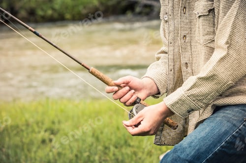 Preview: Cropped view of young man winding fishing reel on fishing rod