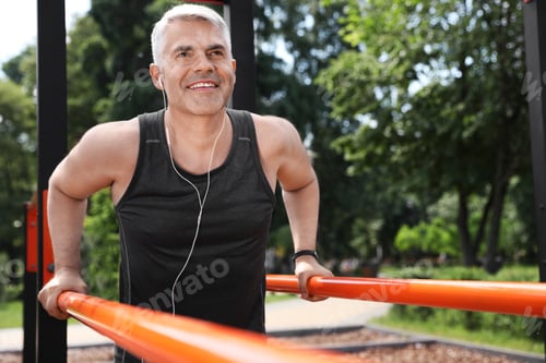 Preview: Handsome mature man doing exercise on sports ground, space for text. Healthy lifestyle