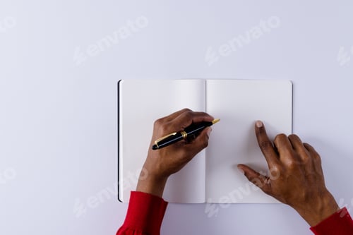 Preview: Hands of biracial man holding pen, writing in notebook with copy space on white background