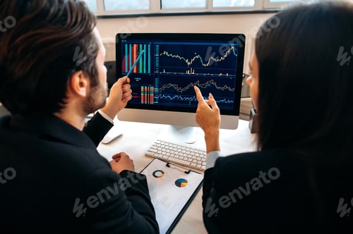 Preview: Successful caucasian colleagues, cryptocurrency traders, man and woman, sit at a table in a modern
