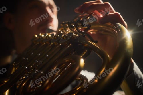 Preview: Golden French Horn Shining in Spotlight during Performance on Stage