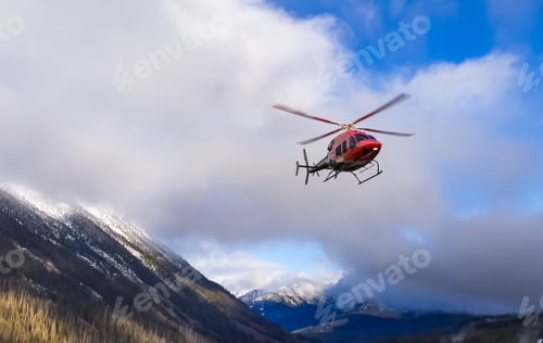 Vista previa: Helicóptero rojo en vuelo sobre las nevadas montañas de Columbia Británica con un cielo azul y nubes dramáticas