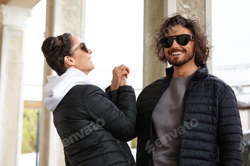 Preview: Couple of young people in jeans clothes posing outdoors over brick wall.A pair of young people in