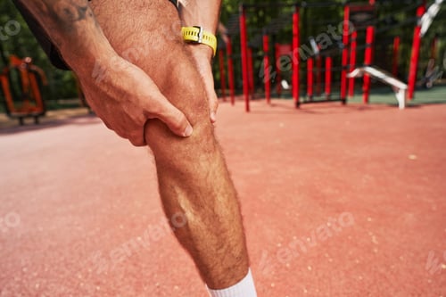 Preview: Sportsman touching his knee during workout outdoors