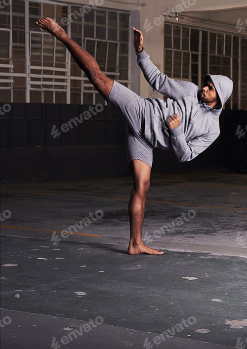 Preview: Shot of a barefoot young man in activewear doing martial arts in a parking lot