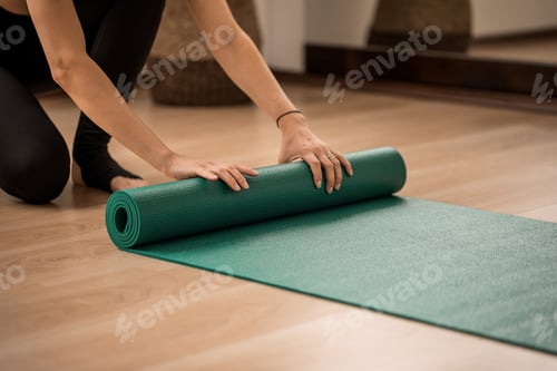 Preview: Woman Rolling Out a Green Yoga Mat