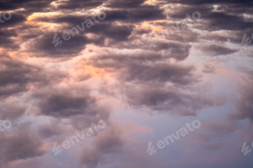 Preview: Landscape photo of big, pink cumulonimbus clouds in a stormy sky at sunset. Moody sunset sky.