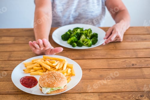 Preview: senior and mature woman choosing broccoli and not hamburger - healthy and diet