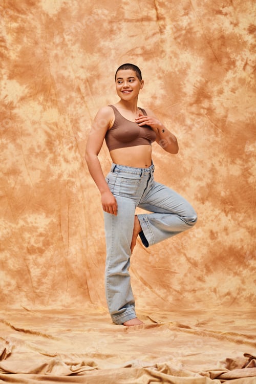 Preview: body positivity, confident, curvy and happy woman in crop top and jeans posing on mottled beige