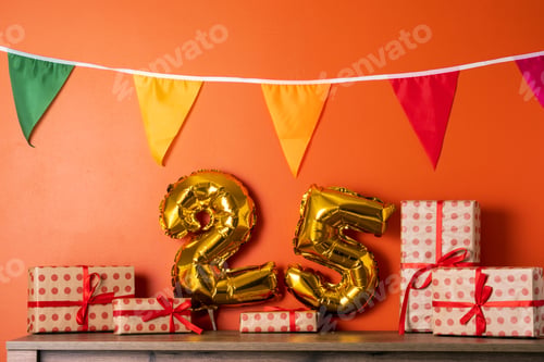 Preview: 25 golden foil balloon numbers party decor on wooden table against orange wall.