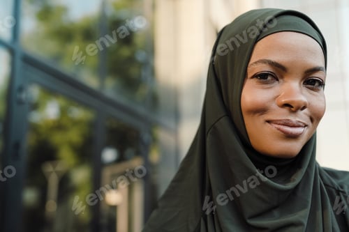 Preview: Woman in headscarf smiles in front of building