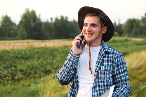 Preview: Young Man Chatting on Phone in Green Field