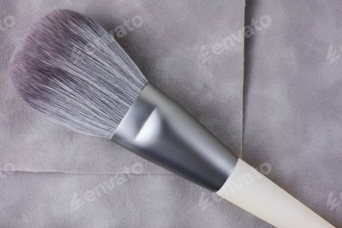 Preview: The large makeup brush is resting on the velor pouch.