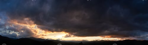 Preview: Dramatic sunset scene with dark, brooding clouds casting shadows over sky.
