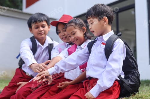 Preview: Group of happy elementary students stacking hands together.