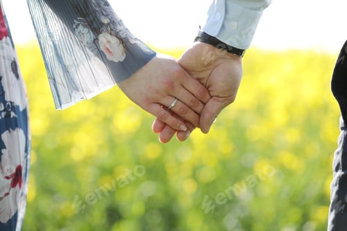 Preview: couple in love hold hands in green field in summer. close up photo