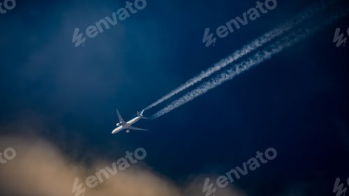 Preview: Commercial passenger aircraft flying over a blue sky, leaving a trail of contrails