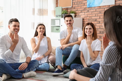 Preview: Group of young people learning sign language with teacher indoors