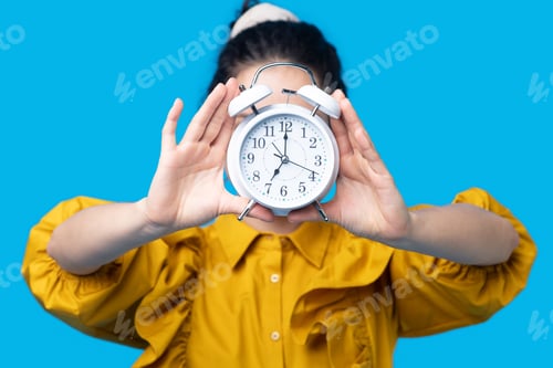 Preview: Woman in a mustard dress holding a clock