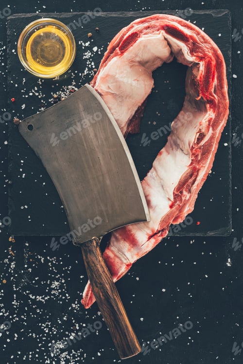 Preview: top view of raw ribs slice with cleaver and oil on stone slate