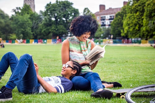 Preview: Boy and mother relaxing and reading book in park
