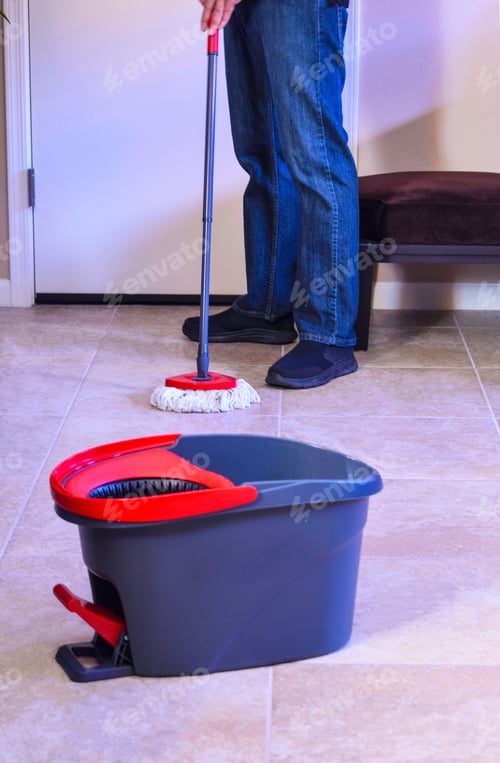 Preview: Man mopping floor at home.