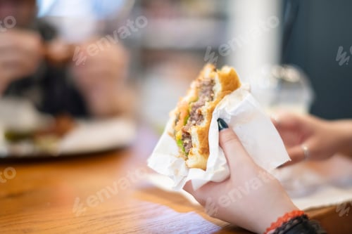 Preview: ↟ The concept of lunch time. An attractive girl eats a delicious barbecue burger sandwich