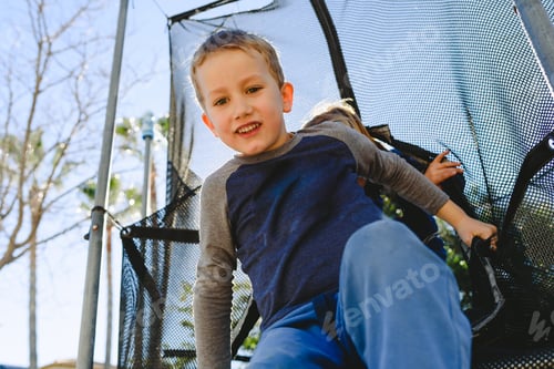Preview: Child having fun in spring on a trampoline at sunset.