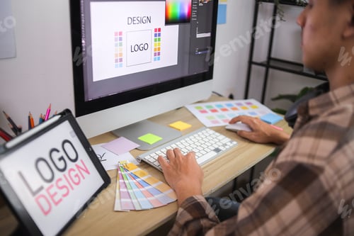 Preview: Closeup of Designer's Hands Using Keyboard and Mouse to Create Logo on Computer Monitor