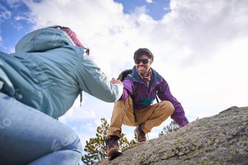 Preview: Hikers helping each other ascending rocky mountain enjoying teamwork and helping hand
