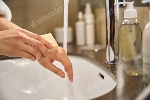 Preview: Water running from tap while woman lathering hands with soap
