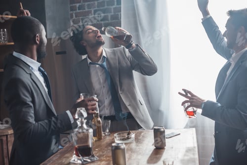 Preview: happy multiethnic friends in suits drinking alcohol and smoking cigars together